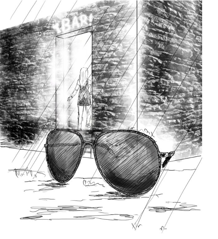 A pair of dark glasses lying on the ground in the rain in the foreground. In the background a figure is entering a doorway to a bar in an alley