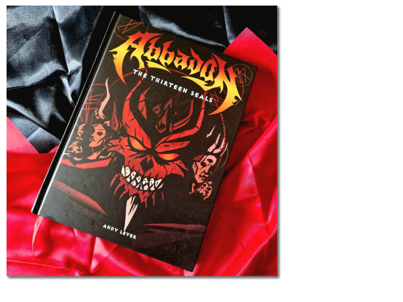The book Abbadon; a black book with a demonic red face, and a flame-like title. Resting on black and red silk